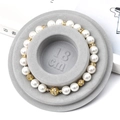 Pearl bead bracelet with gold spacers and hollow flower charm in grey velvet display tray - Flocked Plastic / Grey Sizing Tray (18cm)