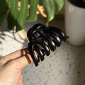 Close-up of matte black pumpkin-shaped hair claw clip held in hand with lifestyle backdrop - Medium(Approx 7cm) / Matte Black