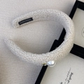 Detail of cream faux shearling headband with pearl accent and handmade label - Headband / Off White