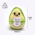 Detail view of a handmade crochet avocado doll holding a white card with text, 8cm tall - Sprout Green Avocado