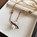 Détail du pendentif chat blanc avec branche en bois et perles sur cordon tressé brun - Collier-Marron-Blanc-Chat