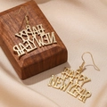 Detailed view of golden Happy New Year letter earrings on silk and wood display - Happy New Year Letters