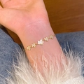 Elegant gold maple leaf bracelet with micro-pave zircons and white inlay on a model wrist - S747 Gold