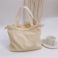 Detailed close-up of cream corduroy tote bag featuring thick straps and drawstring closure - Cream
