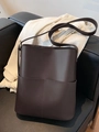 Dunkelbraune Leder Beuteltasche mit Fronttasche und verstellbarem Schultergurt auf Sofa - Dunkelkaffee
