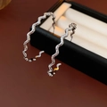 Dettaglio di orecchini a cerchio argento ondulati su una scatola per gioielli nera - Argento