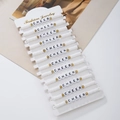 Detail of 14 white polymer clay bead bracelets with gold accents and CHEER letters - 12 Pieces / White