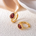 Detail of gold huggie earrings featuring a teardrop red gemstone with vintage milgrain edges - Water Drop Zirconia / Red