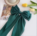 Macro view of a large dark green satin bow hair clip with streamers on a lifestyle setting - Dark Green