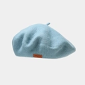 Detail of light blue wool beret with retro brown leather patch and embossed text - Aqua Green