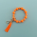 Détail d'un bracelet en perles de silicone orange avec pompon et fermoir doré chic - Orange