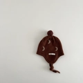 Detail of dark brown knitted baby hat with moon pattern and soft ear flaps and pom-pom - 1-2 years old / Caramel Moon