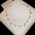 Macro shot of silver necklace with colorful gemstones on white cushion background - Necklace-Multicolor