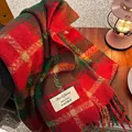 Red and green plaid scarf with tassels in a cozy winter setting with a warm lamp - Christmas Plaid Red