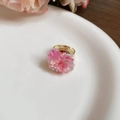 Detalle de anillo de resina floral con banda dorada ajustable y pétalos rosas - Estilo Rosa