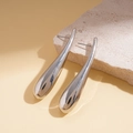 Macro shot of silver teardrop earrings resting on a textured beige stone base - Silver
