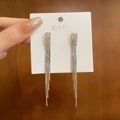 Makroaufnahme von silbernen Quastenohrringen mit glitzernden Strasssteinen und langen Fransen - Silber Quadratische Quaste