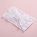 Close-up detail of a soft white jacquard nylon baby headband with a large decorative bow - White