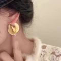 Detailopname van gouden vintage spiraalvormige oorbellen op een model met metalen glans - Gouden Spiraal Textuur