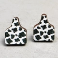 Close-up of wooden cow tag earrings featuring a classic black and white cow print pattern - 9-Cow Print Ear Tag