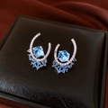 Macro view of silver earring featuring a hexagonal blue gemstone and pavé diamonds - Crescent Blue Gemstone Pave Stud Earrings