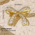 Goldene Schleifenbrosche mit Strasssteinen und Maßangaben auf beigem Strukturpapier - Goldene Schleife Voll Eingelegt (BRS-J437G)