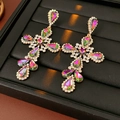 Detalle macro de pendientes de cruz vintage dorados con cristales irisados en cuero negro - Dorado-Verde (Aguja de Plata S925)