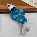 Detalle de cerca del colgante en forma de pez con cuentas de ojo turco azul y escamas de plata - Pinza de pico de pato (Azul) / Azul - Lado derecho