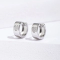 Macro shot of silver heart huggie earrings with cubic zirconia pavé and polished metal - 9mm / Silver
