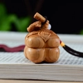 Macro shot of hand-carved wood persimmon pendant with natural grain on a book - Cypress Single Persimmon Charm