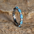 Exquisite silver eternity ring featuring vibrant blue opal stones set on a warm rocky surface - Platinum Blue Opal