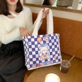 Detail der lila karierten Canvas-Tasche mit weißem Plüschgriff und Cartoon-Bär - Schachbrett-Bär