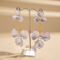 Detail shot of purple flower earrings with gold stems and pearls on a clear stand - White