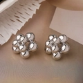 Silver flower stud earrings crafted from metallic spheres on a textured beige background - Silver