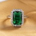 Macro shot of rectangular emerald-cut gemstone ring with sparkling diamond halo setting - Silver (Green Stone)