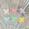Macro shot of colorful translucent resin X-shaped charms on iridescent shell pattern tray - Letter X