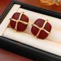Detalle de pendientes cuadrados rojo oscuro con patrón de cruz dorada en joyero - Rojo Vino (Aguja de Plata 925)