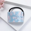 Close-up of marble pattern acetate hair tie in blue and pink on white display stand - Blue