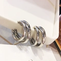 Macro shot of polished silver multi-layer hoop earrings on a cream display stand - Silver