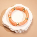 Détail de segments en résine marbrée orange avec perles en métal doré sur pierre - Forme de Nœud de Bambou / Rose Pêche