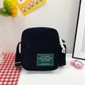 Minimalist black corduroy square crossbody bag with green woven label and shoulder strap - Black