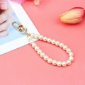 Porte-clés en perles de verre blanc avec fermoir mousqueton doré sur fond rose - Perle Blanc Crème + Boucle KC