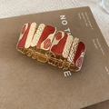 Dettaglio di un bracciale elastico dorato con smalto rosso e trama martellata - Oro-Rosso