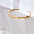 Detail eines goldenen wellenförmigen Armreifs auf einem weißen geometrischen Prisma - Mini-Wellenkurve Offene Manschette (Gold)