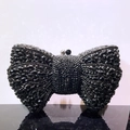 Close-up of black bow-shaped clutch bag with sparkling rhinestones and bead clasp - Black