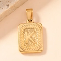 Detailed macro shot of vintage gold square pendant with embossed letter K texture - Letter K