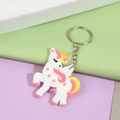 Cartoon unicorn silicone keychain with silver ring on a pink and green background - Unicorn