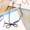 Gros plan d'une pince à cheveux à perles argentées avec un nœud noir en tissu satiné - Collier Nœud Perle Argentée Nœud Noir