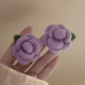Macro view of velvet-textured purple flower earrings with green leaf accents - Purple