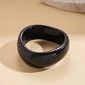 Nahaufnahme eines schwarzen Acryl-Armreifs mit Hochglanz-Finish und Wellenstruktur - Unregelmäßig Geschwungener Breiter Armreif / Hellschwarz